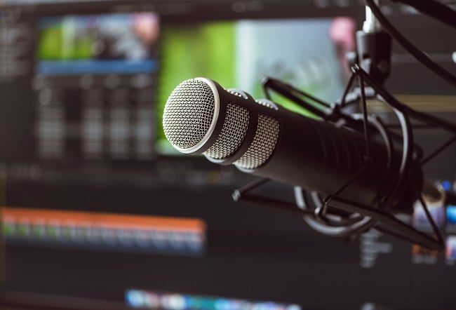 Microphone in front of blurred computer screens.