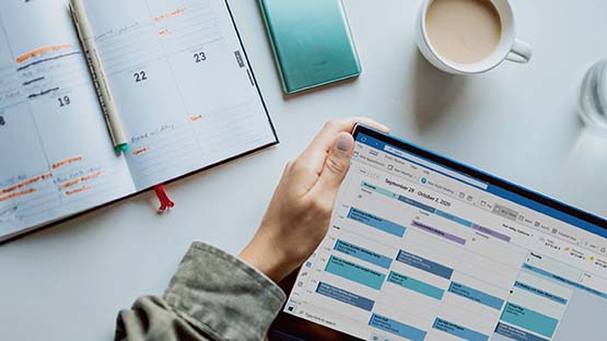 digital calendar open on laptop screen, with desk and coffee mug in background