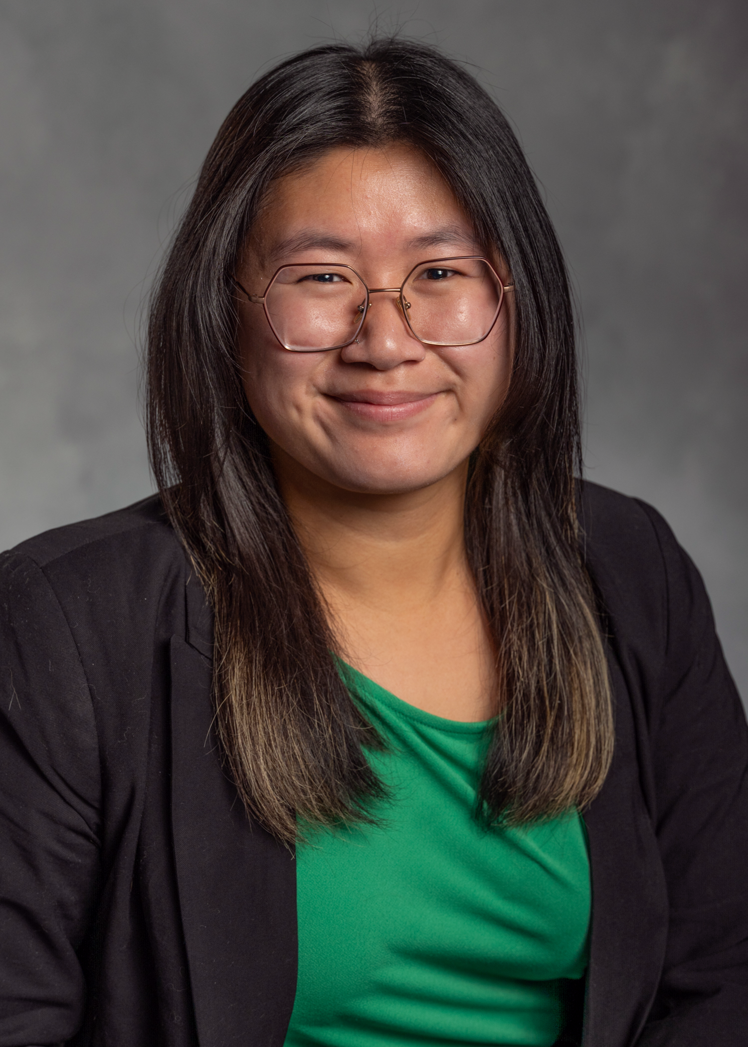 Liana Mann smiling at the camera wearing a dark blazer over a green blouse.