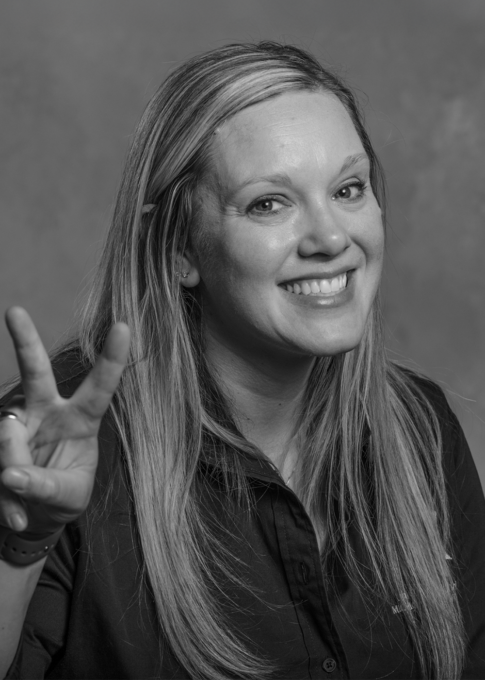Rachel Mercier smiling and holding up her hands to make a peace sign.