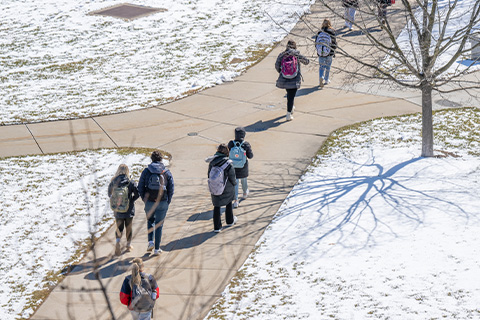 An aerial view of MSU's campus showing a section of sidewalk with students walking on a bright winter day.