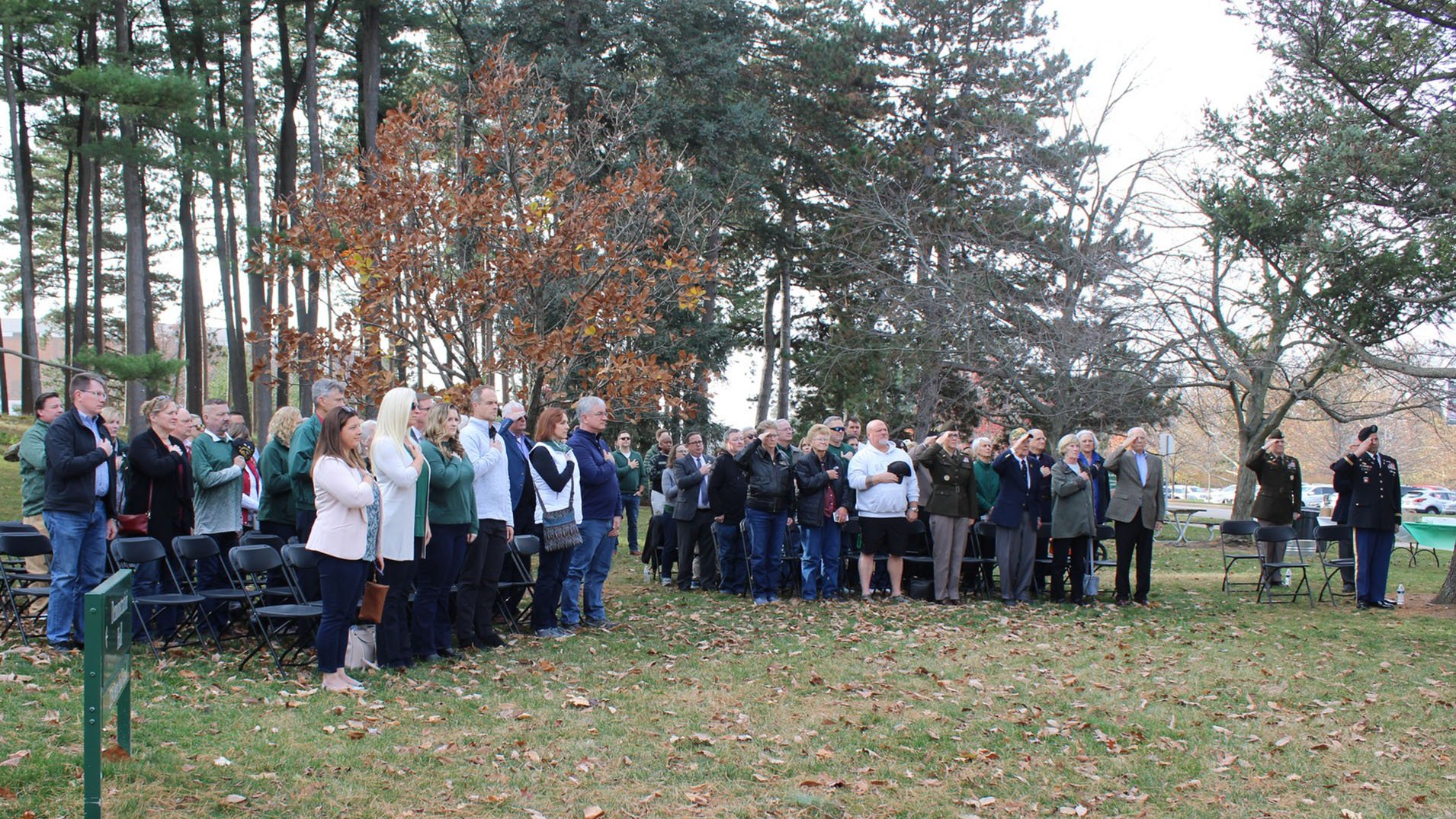 attendees stand each with a hand on their chest