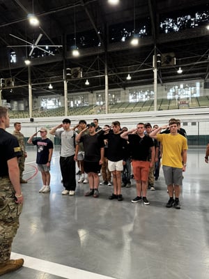 Cadets standing in formation saluting during activities during First-Year student orientation