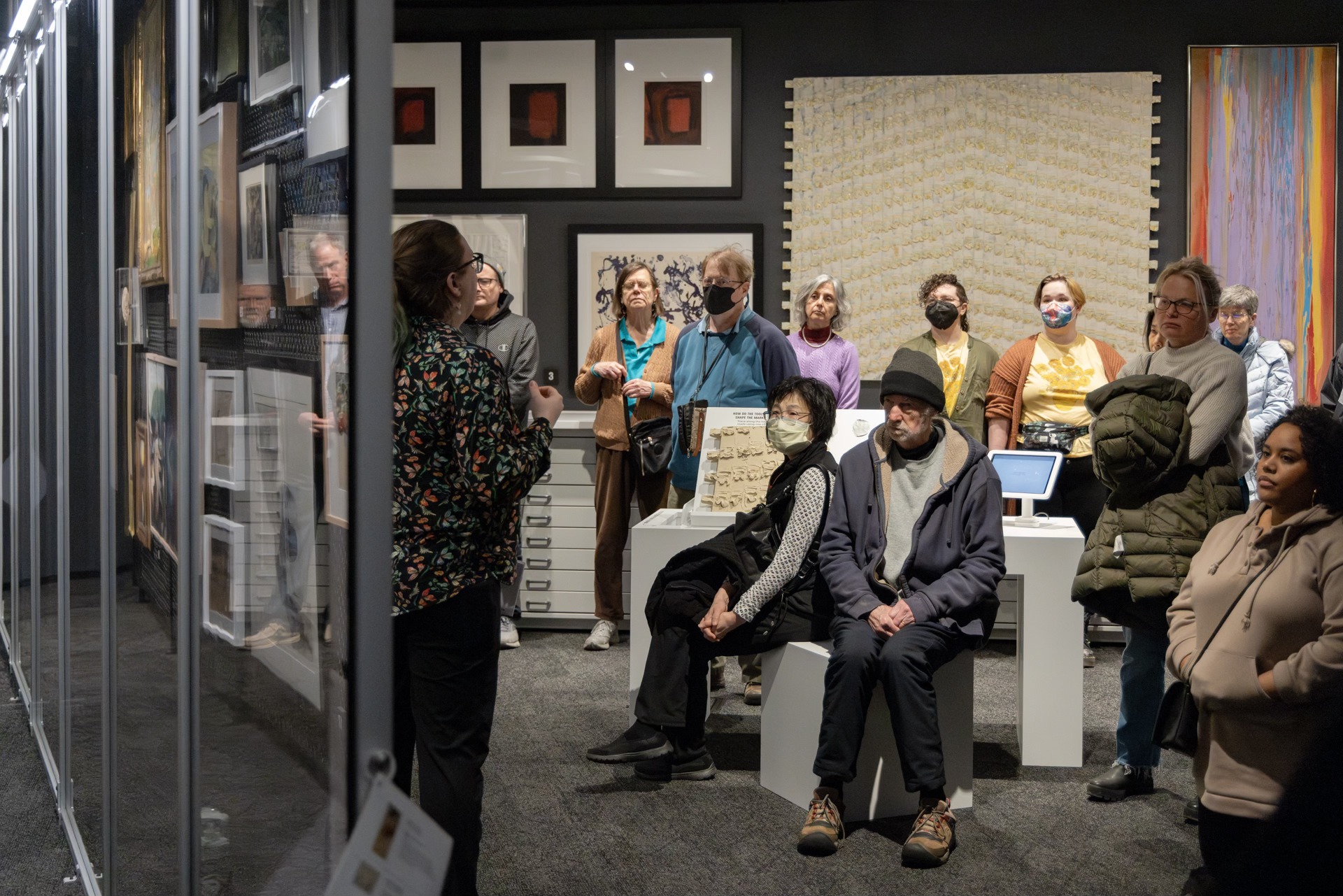 group of people listening to a woman speaking in an art museum