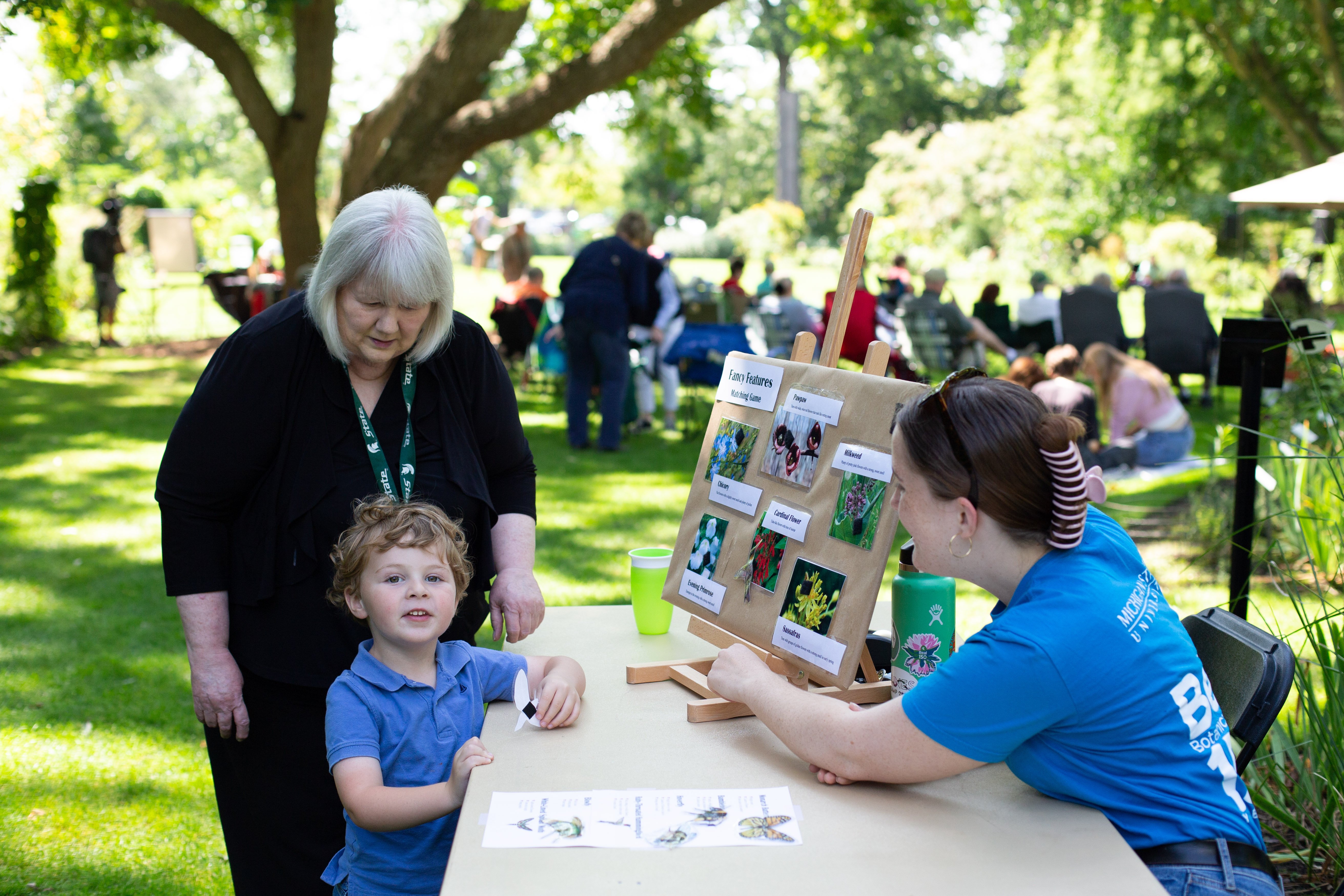 an older woman and a child doing an activity at an outdoor event table