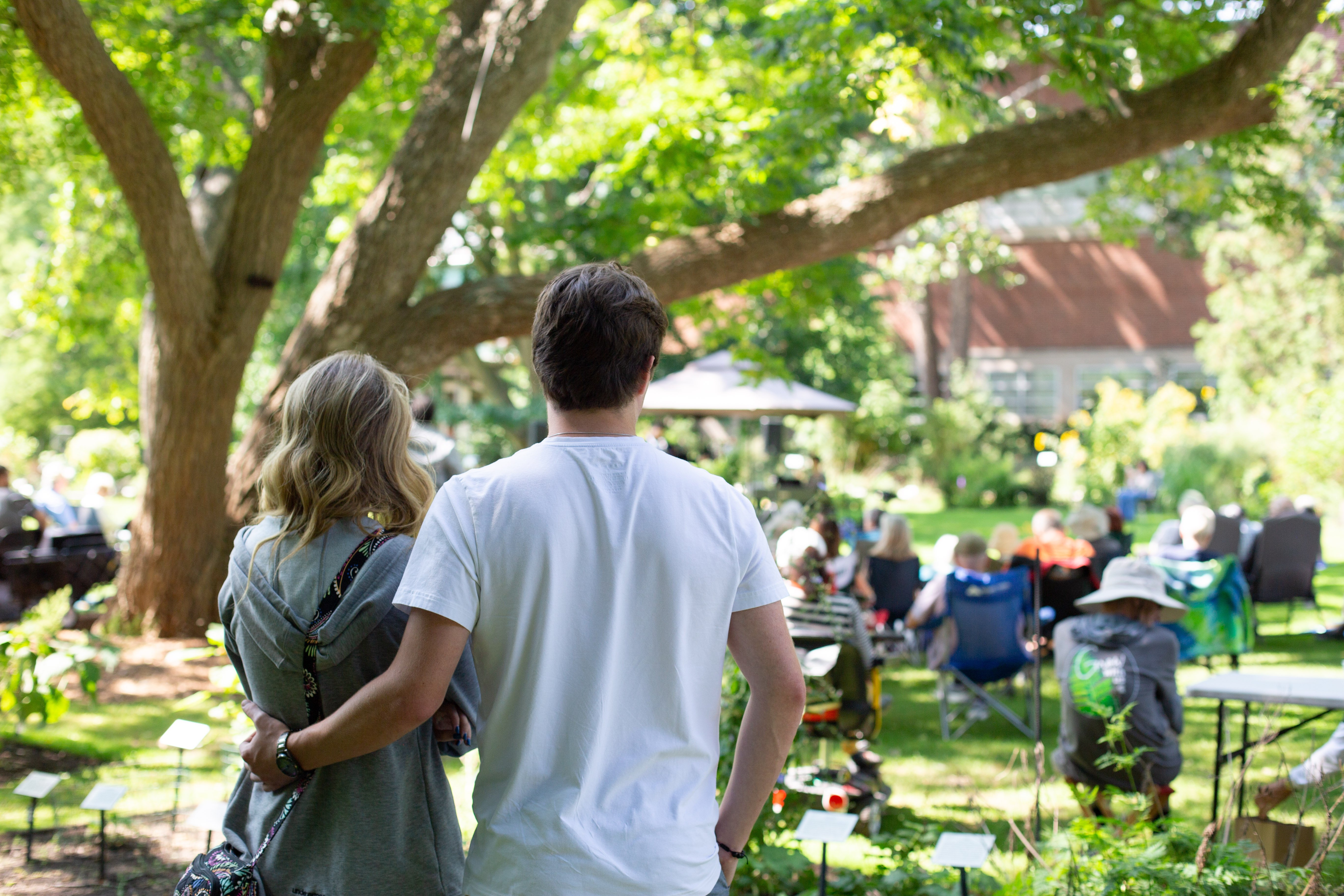 photo of a couple watching an outdoor concert, man has arm wrapped around woman's waist