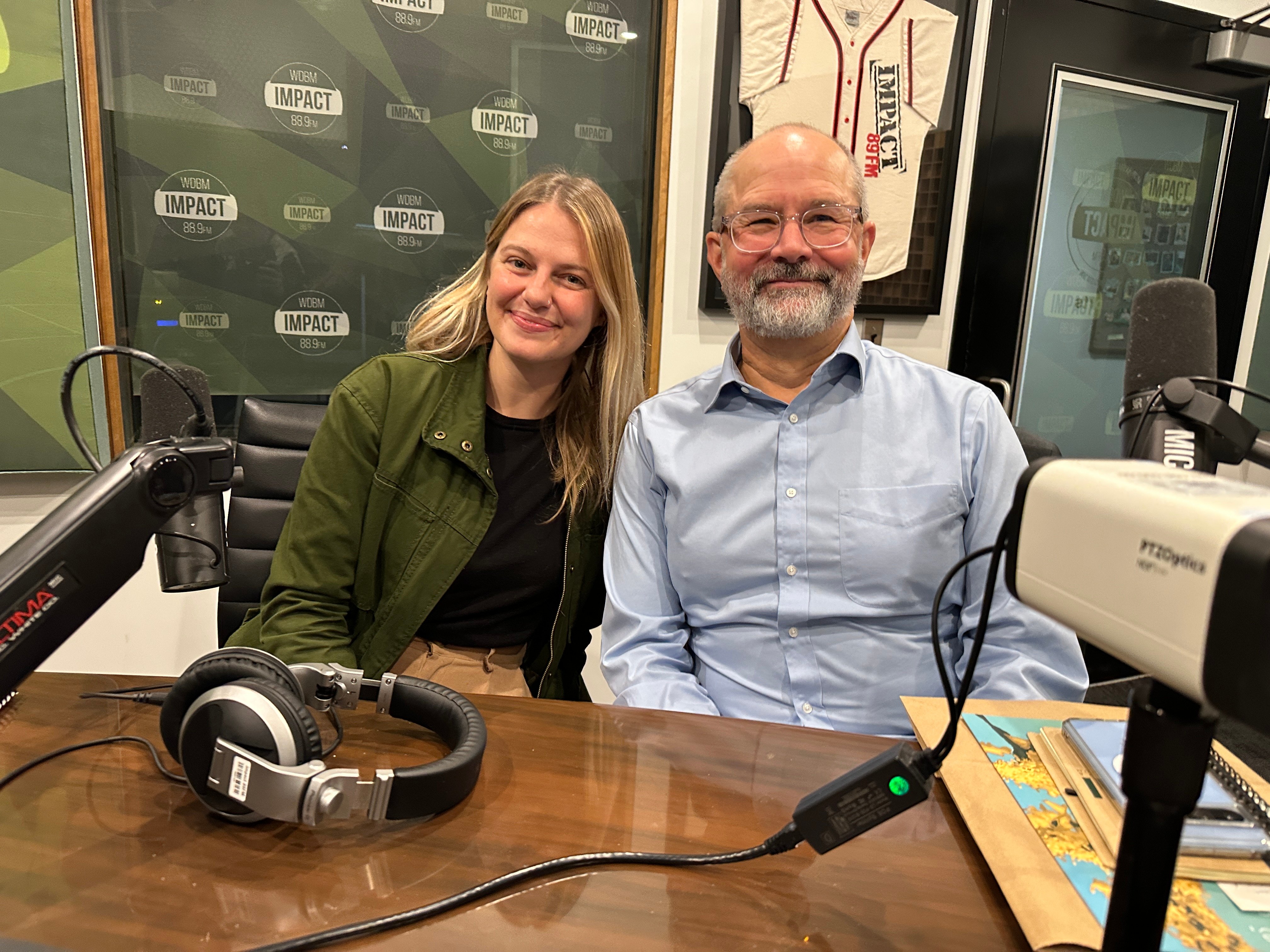 man and woman sitting in a recording studio smiling at camera