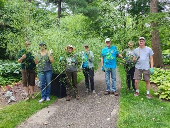 group of people posing with large weeds pulled from a garde