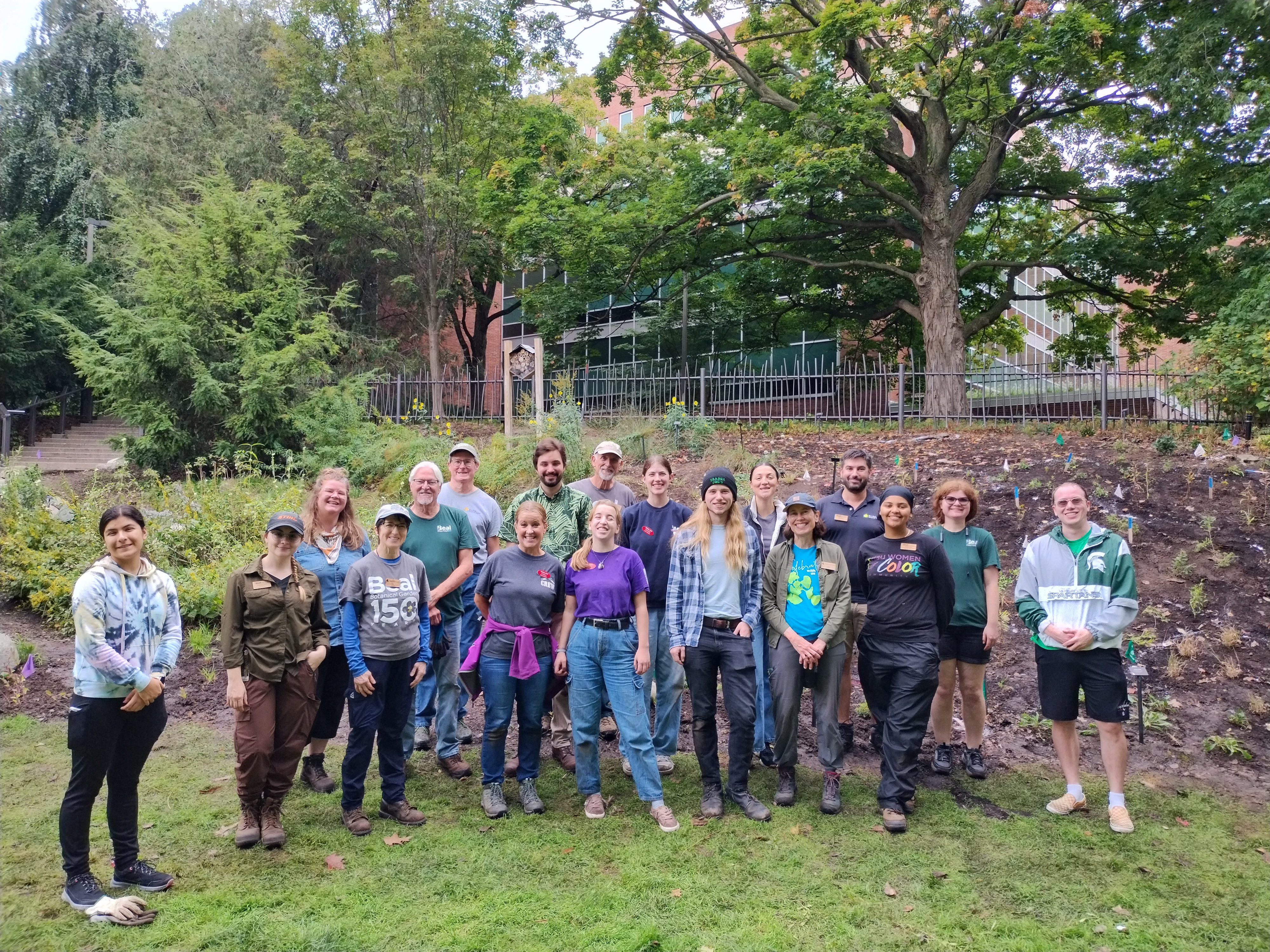 group of volunteers posed for a photo in front of a newly planted garden hillside