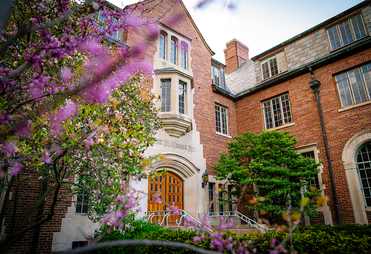 Campbell hall, with focus on front door of a red brick building and spring flowers