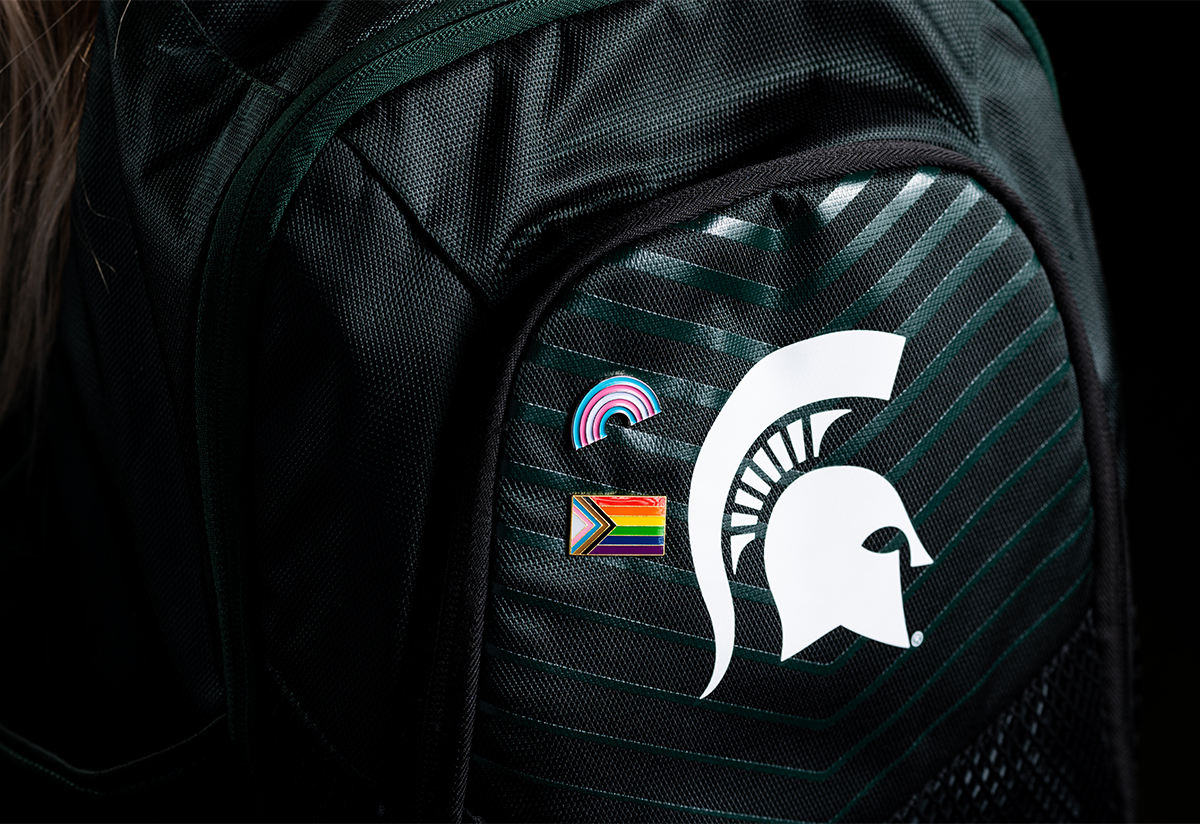 a black backpack with a spartan helmet logo and Pride pin