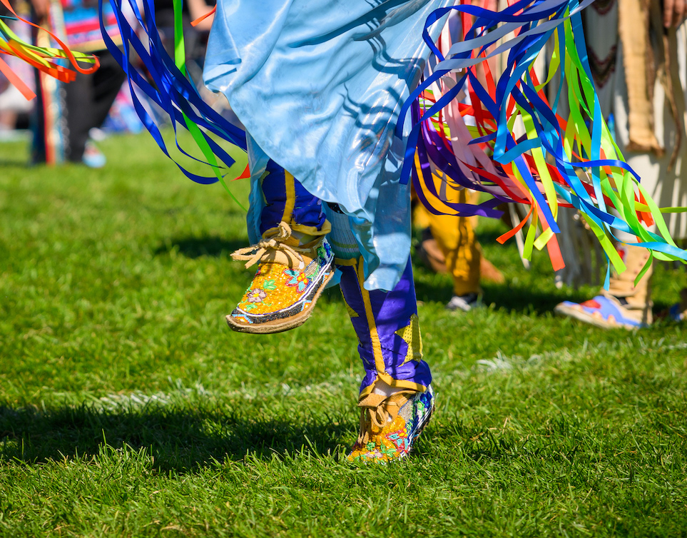 Close up of North American Indigenous dancer's dress and moccasins while dancing at a powwow.