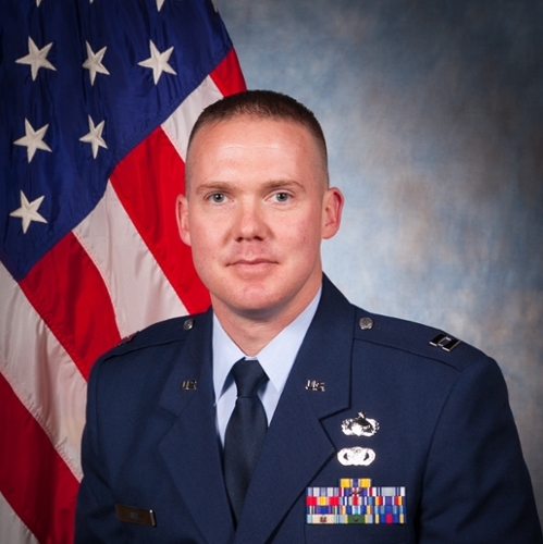 Headshot of Cailean Gee in front of a professional background and an American Flag.