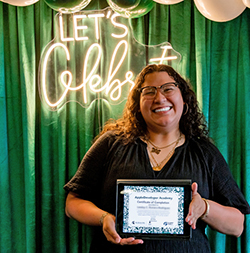 A learner poses with a certificate of completion from her graduation.