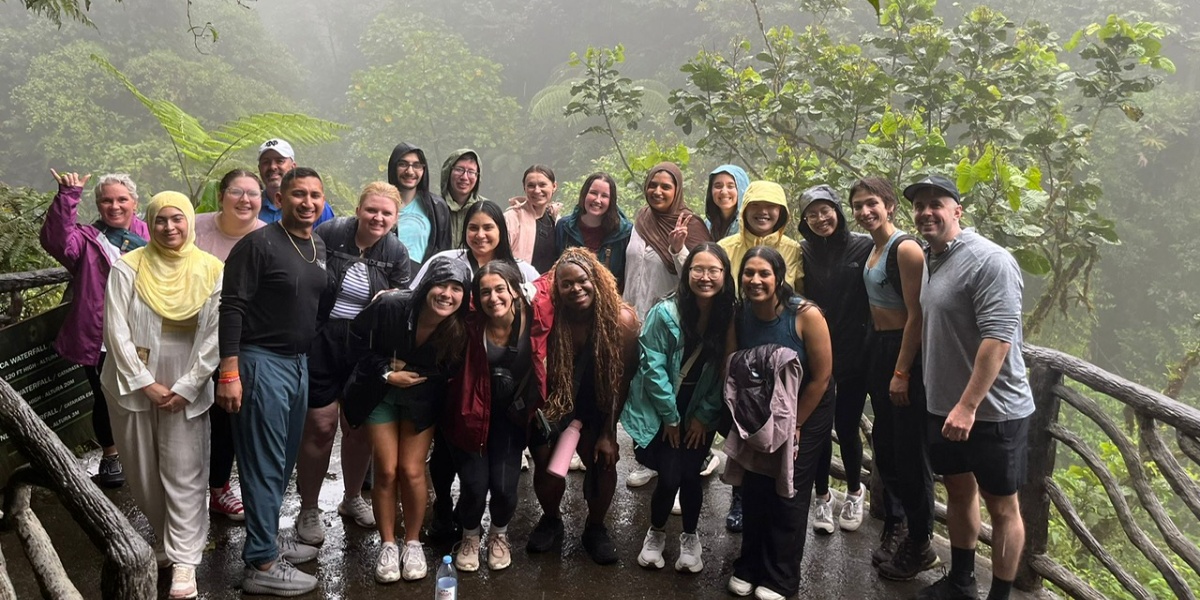 MSU College of Osteopathic Medicine students and faculty taking a group photo in front of a waterfall