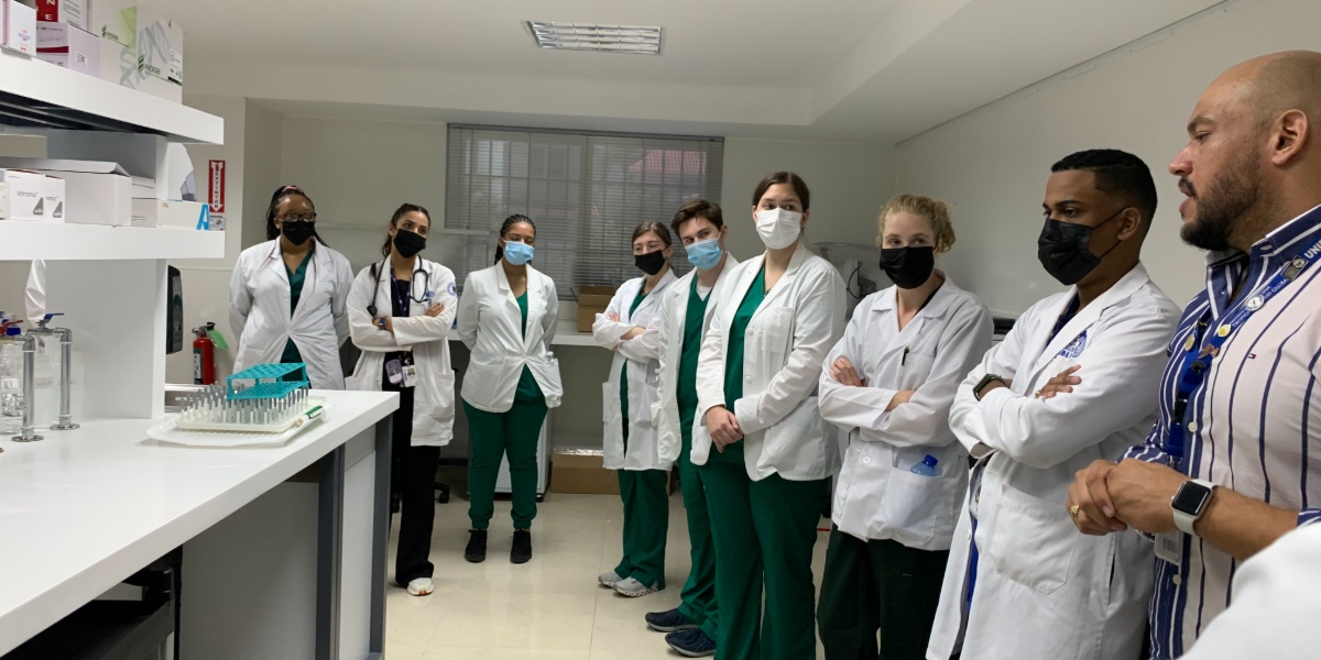 MSU students in lab coats listening to a local physician inside a Dominican hospital lab