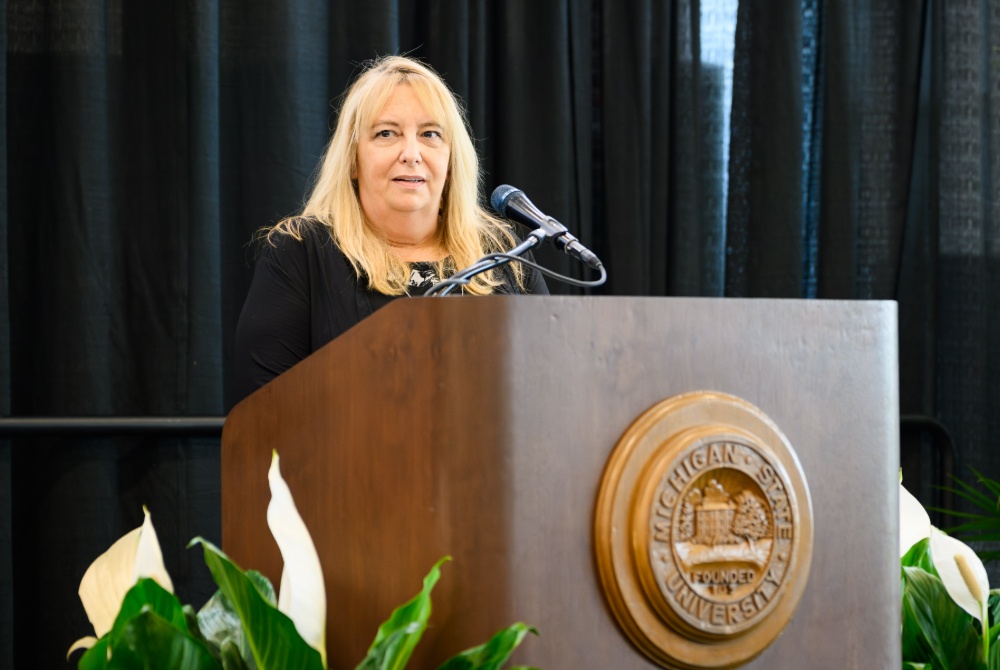 Stephanie Six speaking behind a podium at the 2026 MSU Staff Awards Ceremony