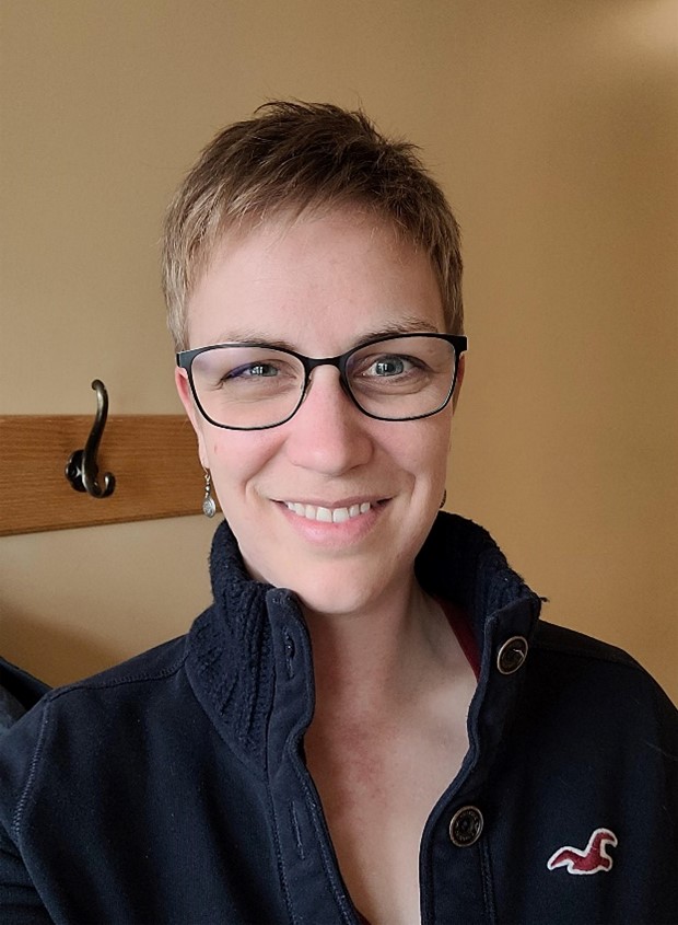 Clara Graucob wearing a black button-up shirt and glasses.