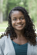 Tashal Brown in a teal shirt and grey jacket, standing outside.