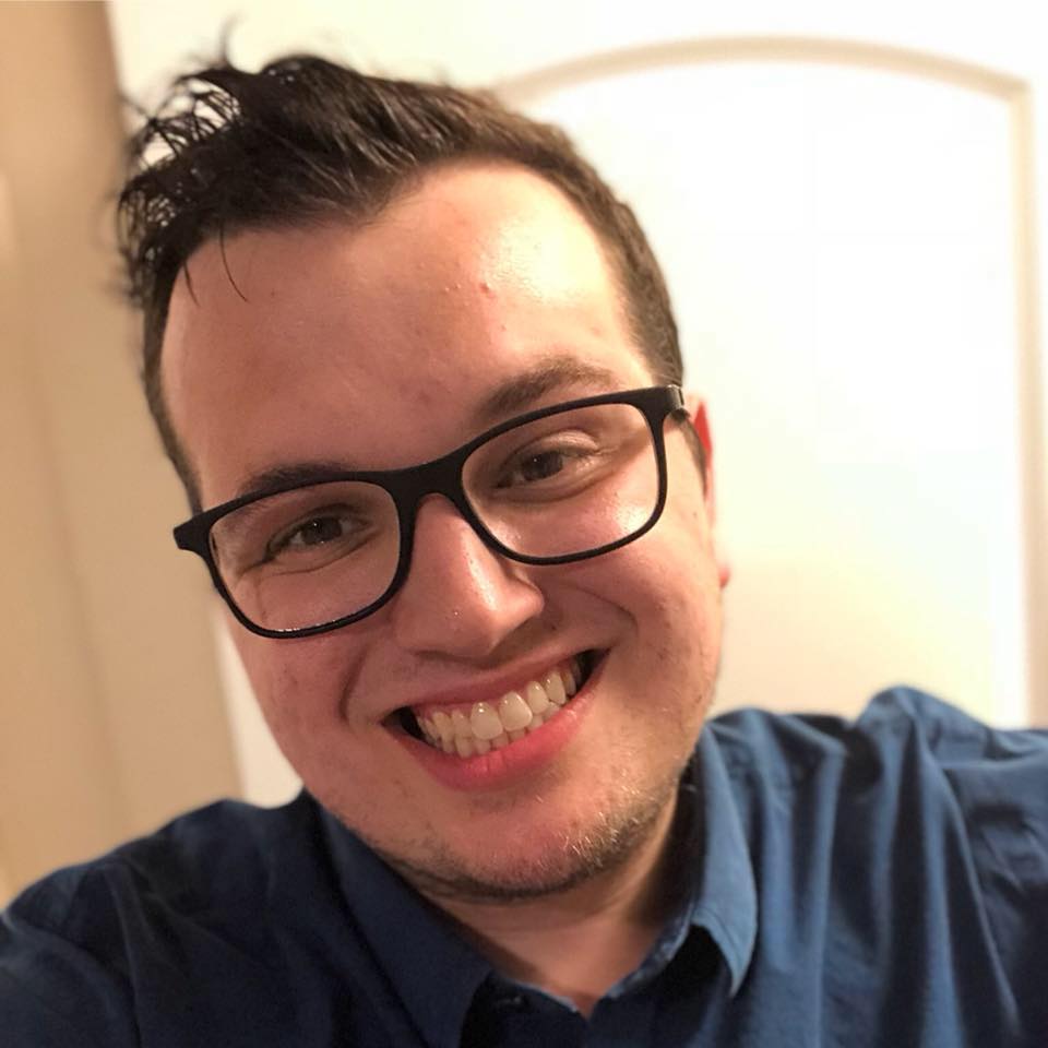 Nick Sanders in a blue shirt and black glasses.