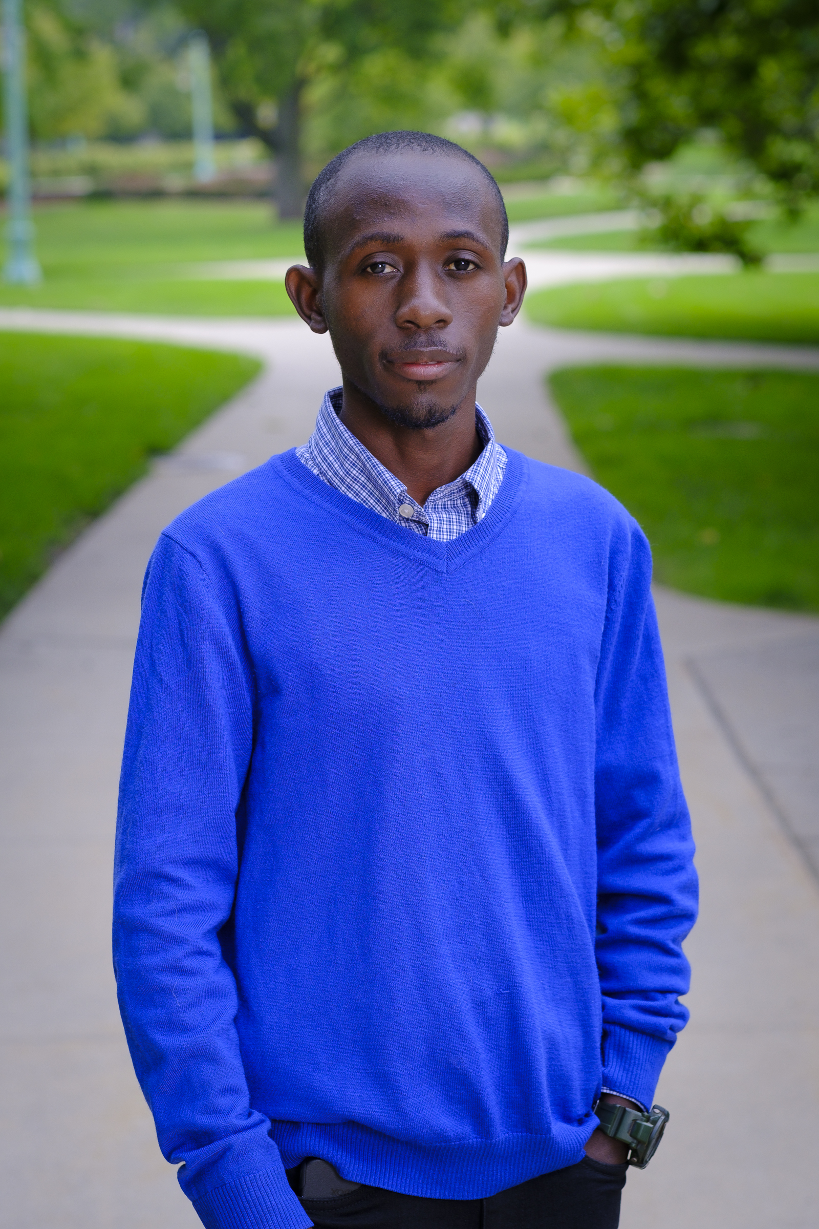 Ibrahim, standing outside in a vibrant blue sweater.