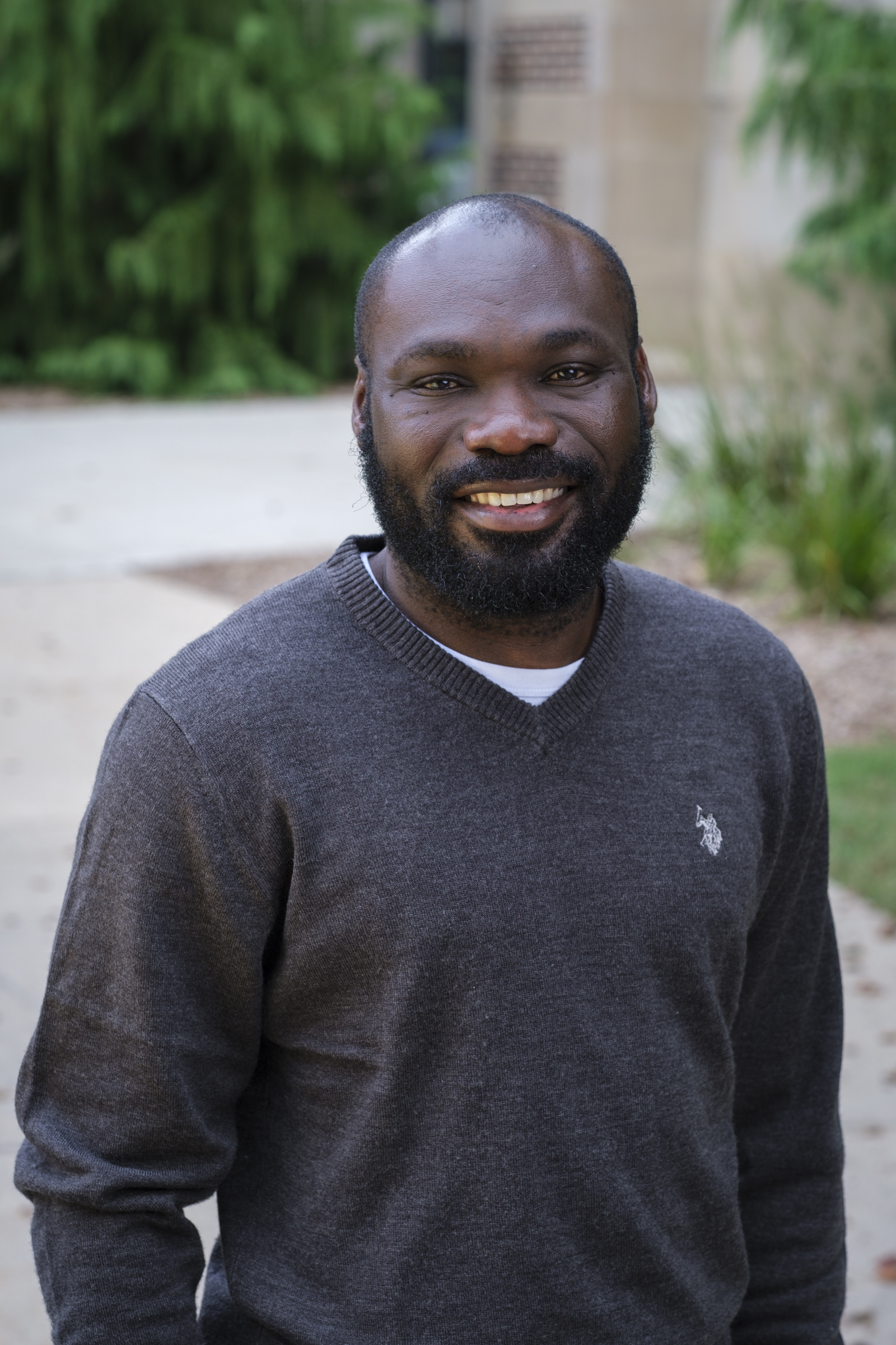 Prince Owusu standing outside, wearing a black polo.