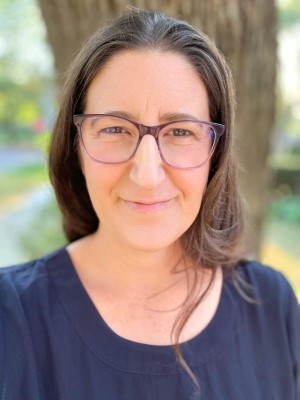 Teena Gerhardt wearing a blue shirt and standing in front of a tree.