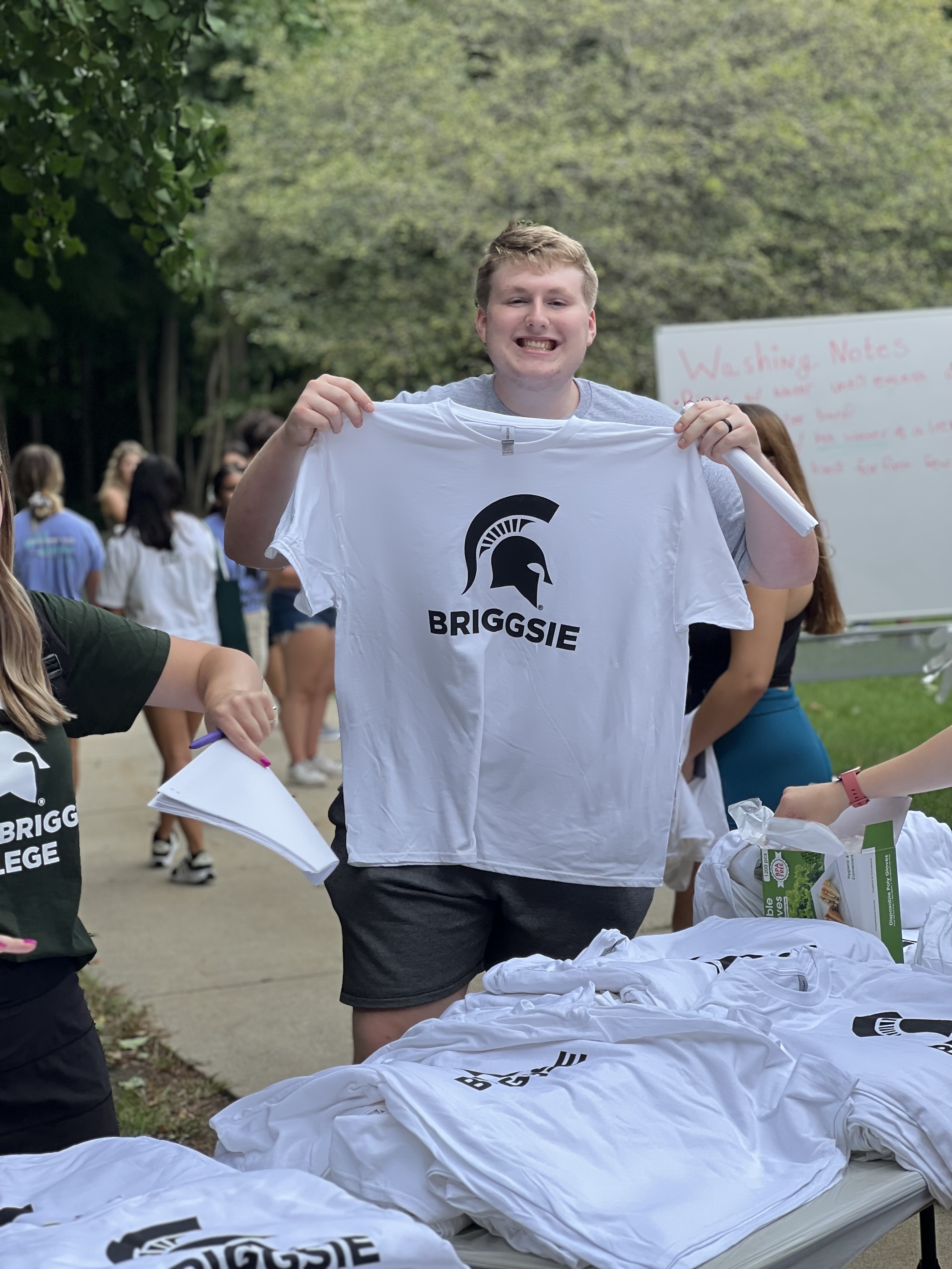 A student holding up a Spartan t shirt and smiling.