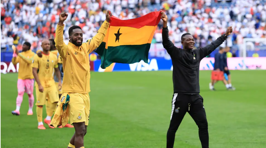 Members of Ghana's national soccer team carry a Ghanaian flag on the field after a World Cup match.