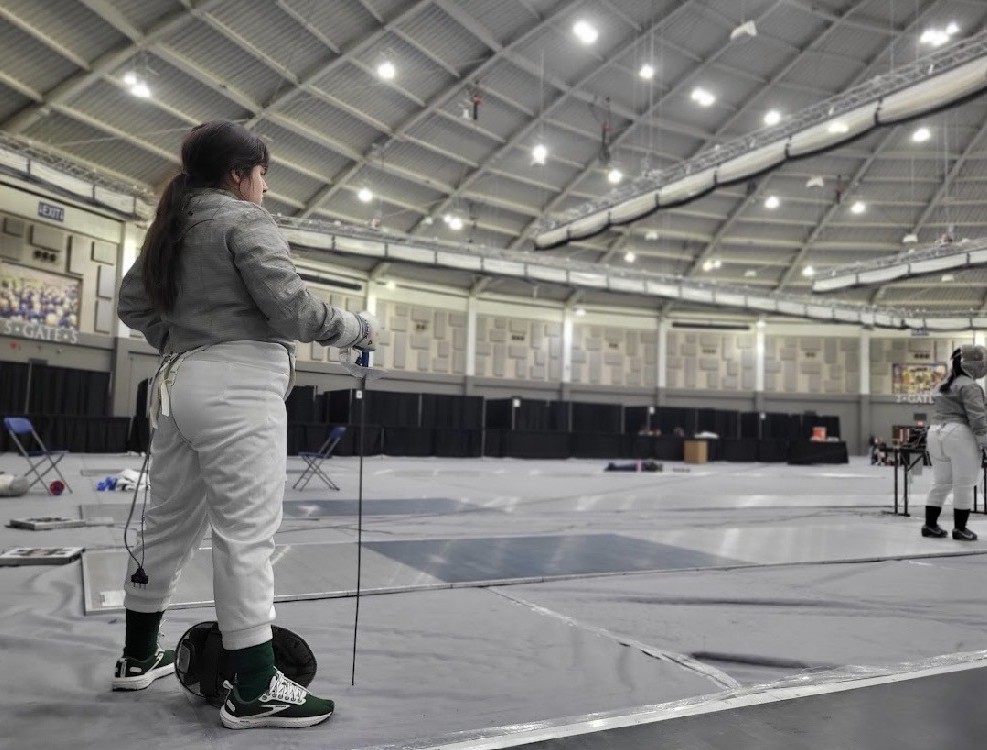 Zoe Larsen getting ready for fencing competition. She is dressed in her fencing gear.
