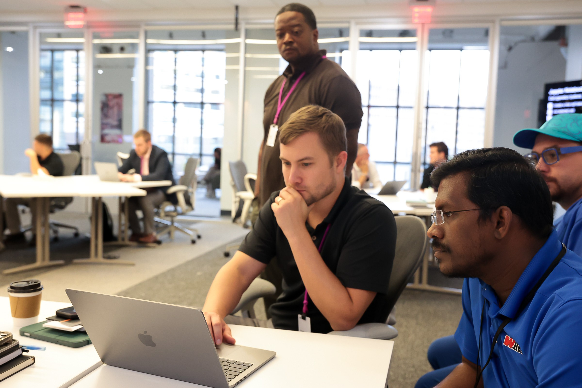 Four people working together on a Macbook.
