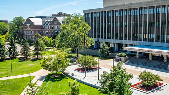 The Hannah Administration Building, viewed from a high window in Olds Hall. The plaza, John Hannah statue and trees in front of the building are visble on a sunny day.