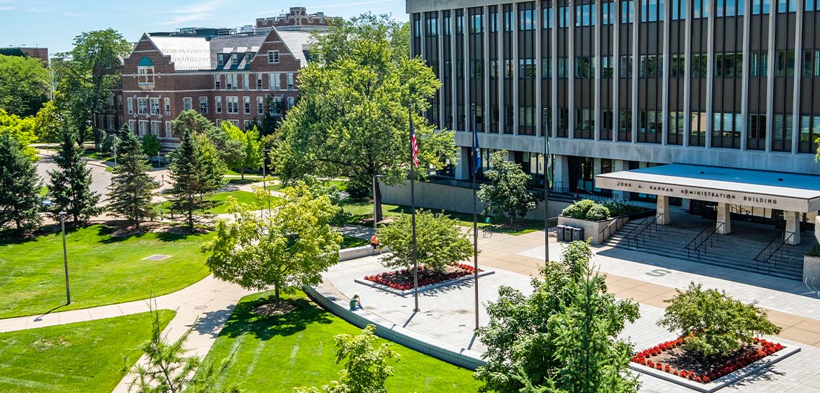 The sun shines on the plaza in front of the Hannah Administration Building, viewed from above in Olds Hall.