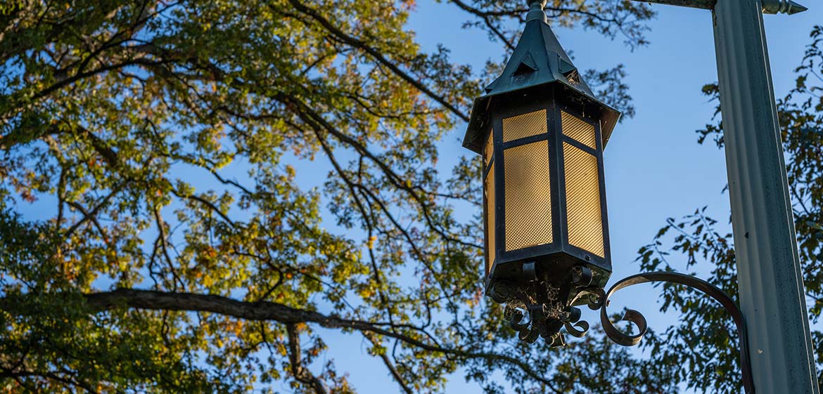 A historic lantern lights the way among the trees on the north end of campus.