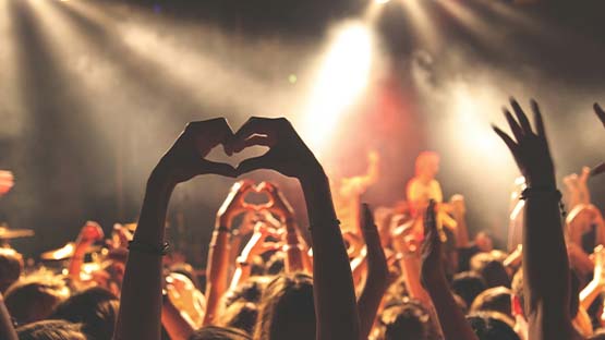 Audience members holding up hands in the shape of a heart