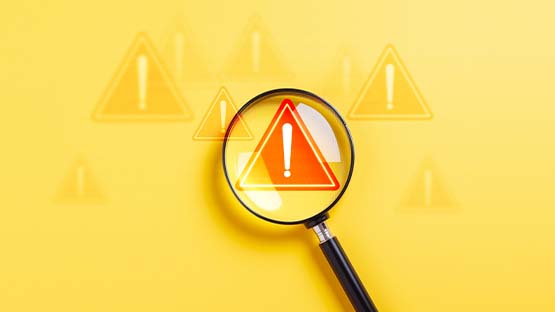 A magnifying glass is focused on an alert emergency icon sign, on a yellow background