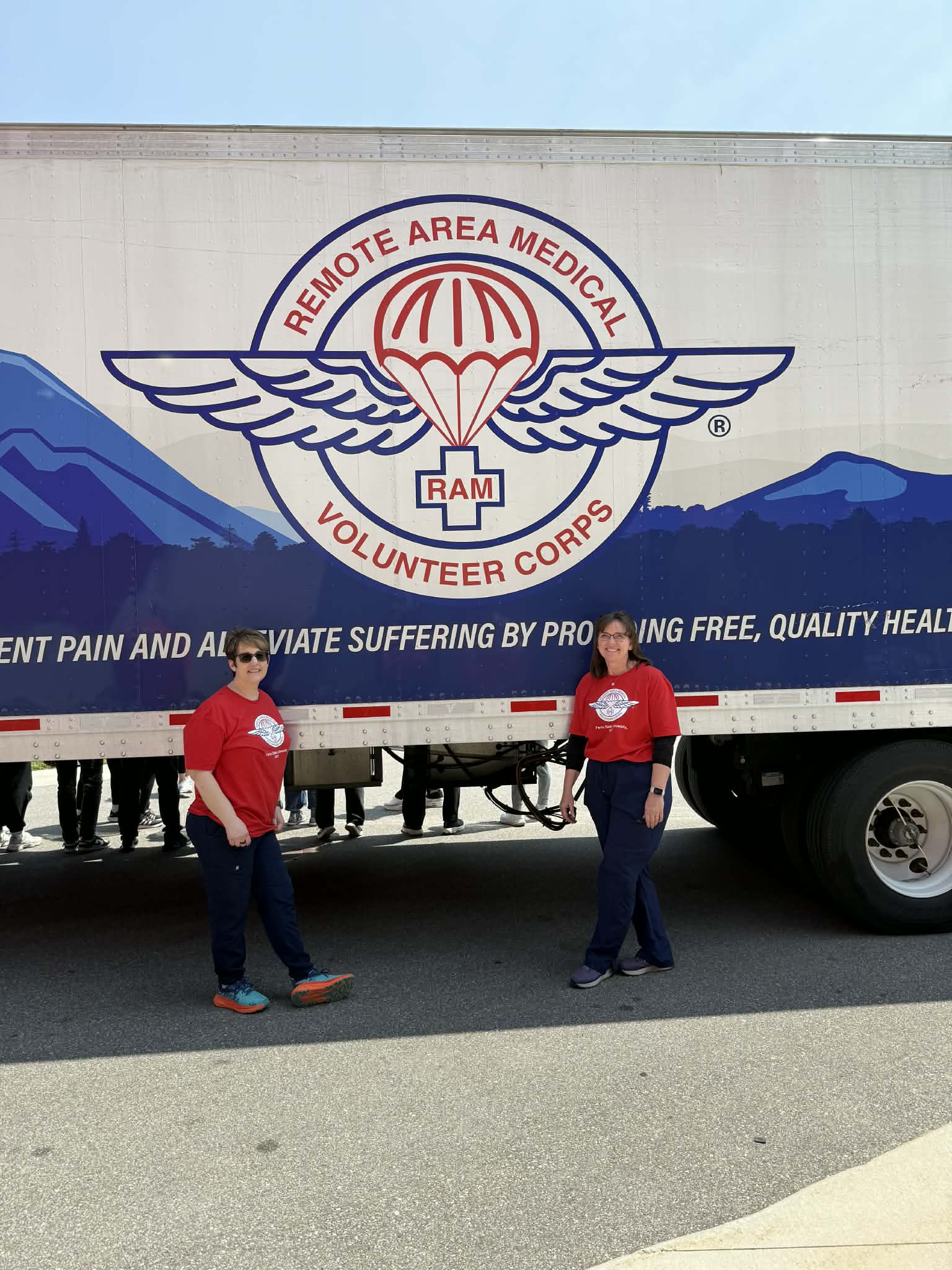 Two volunteers standing in front of the Remote Area Medical Volunteer Corps Semi Truck. 