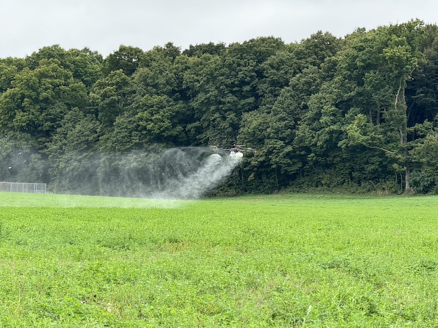 A drone sprays liquid on a farm field 
