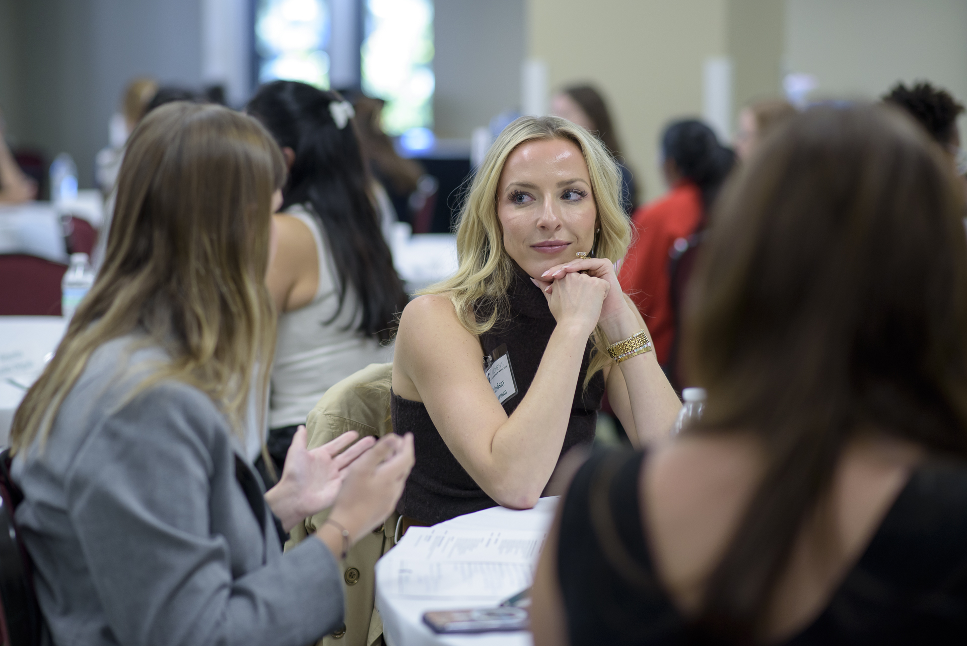 Women talk with each other around a table.