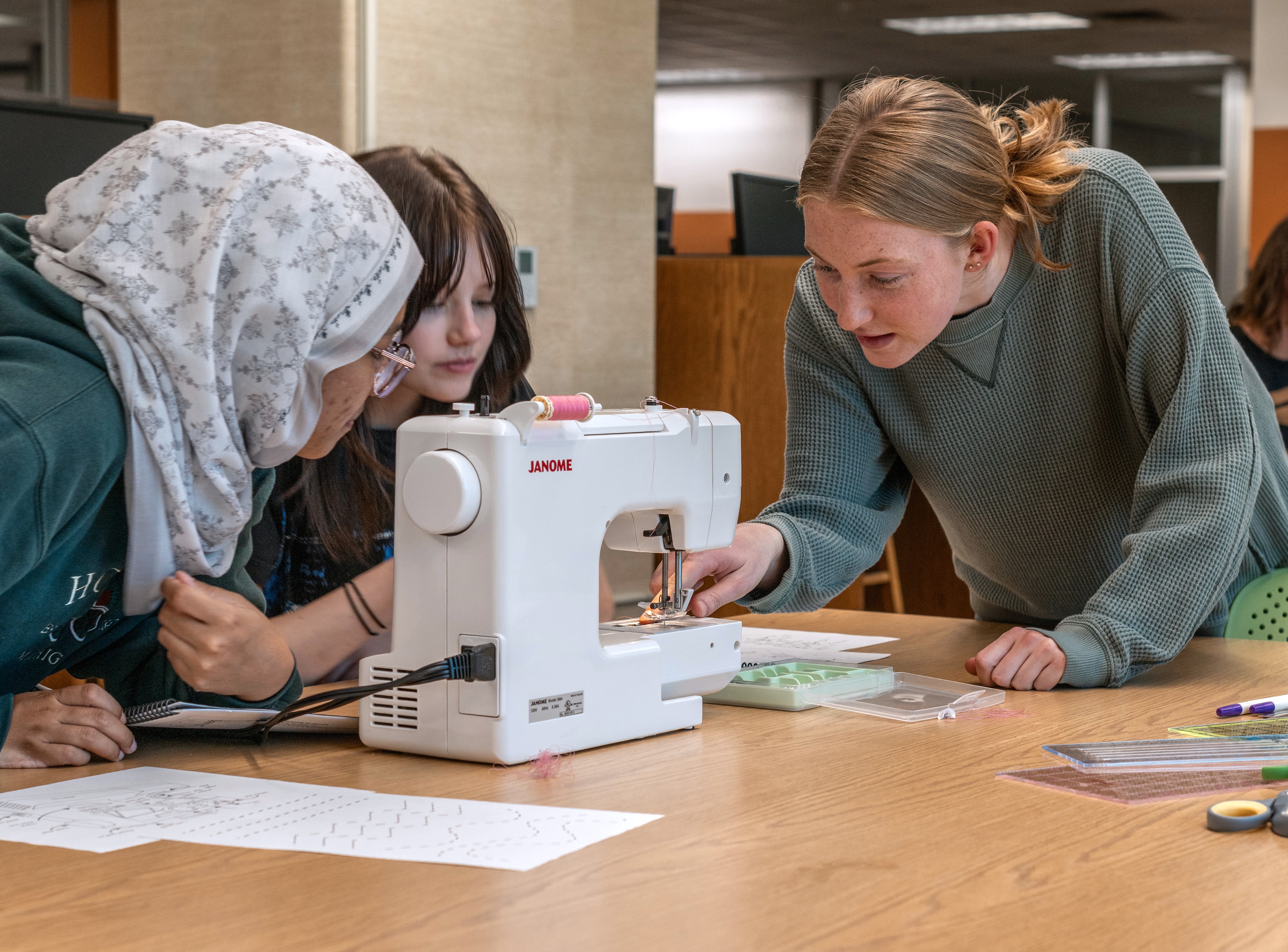 Students using sewing machine.