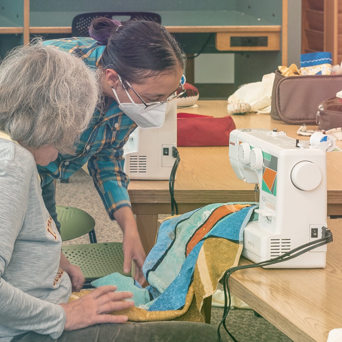 Two women working on a sewing machine. 