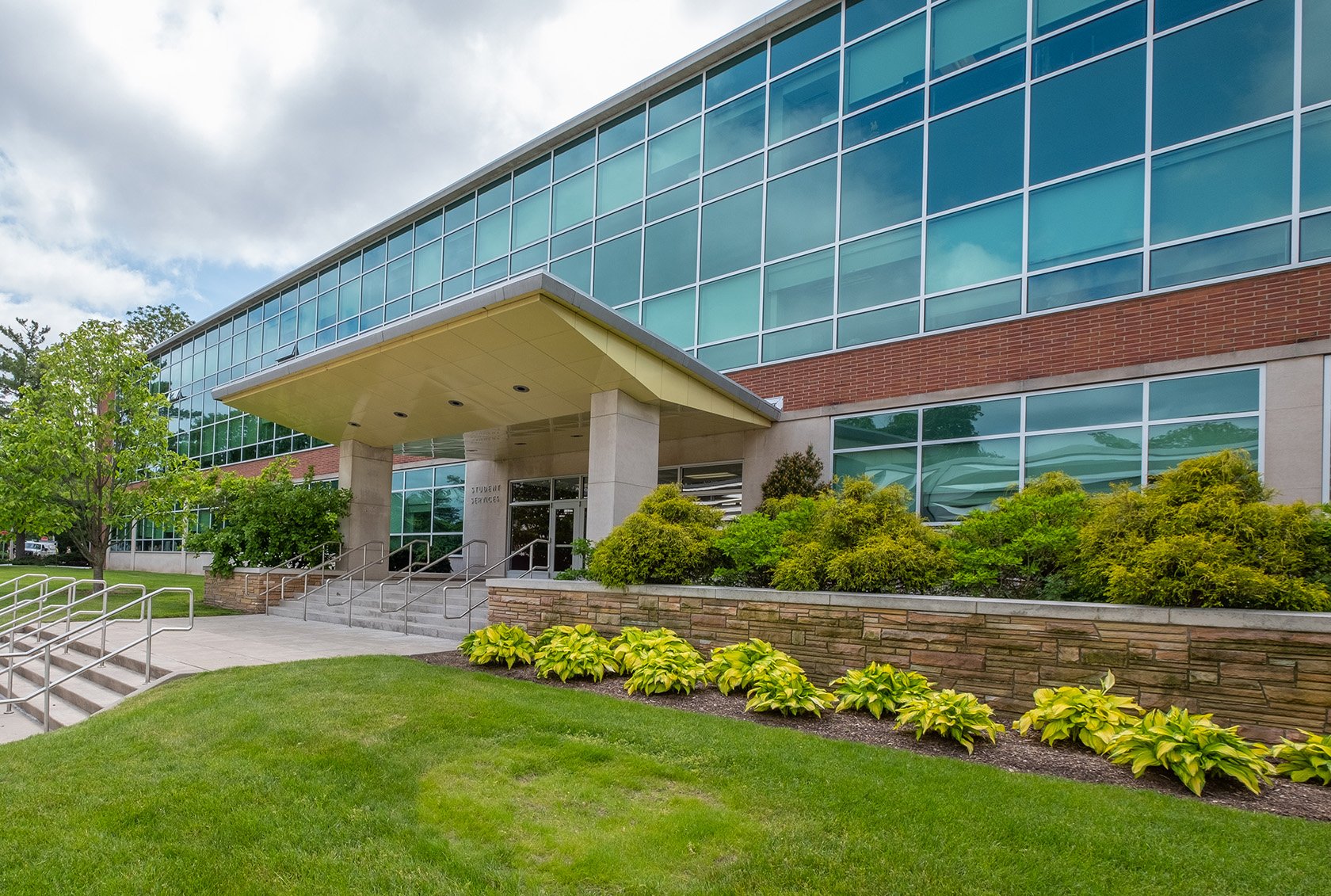 The Student Services building on a sunny day. Flowers bloom in front of the building.