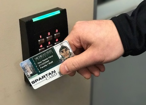 A person scans their MSU ID on a keypad.
