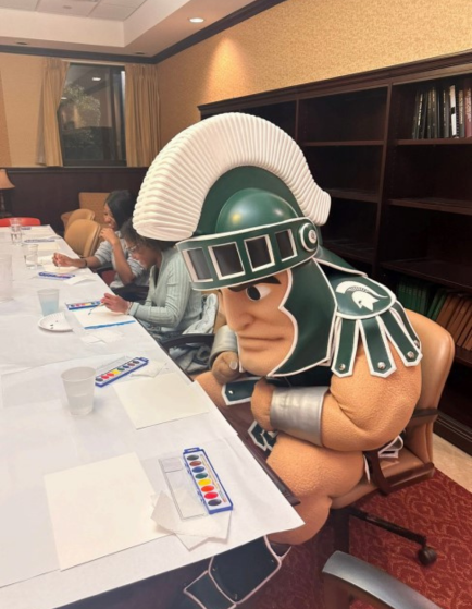 Sparty Mascot painting at desk with other students