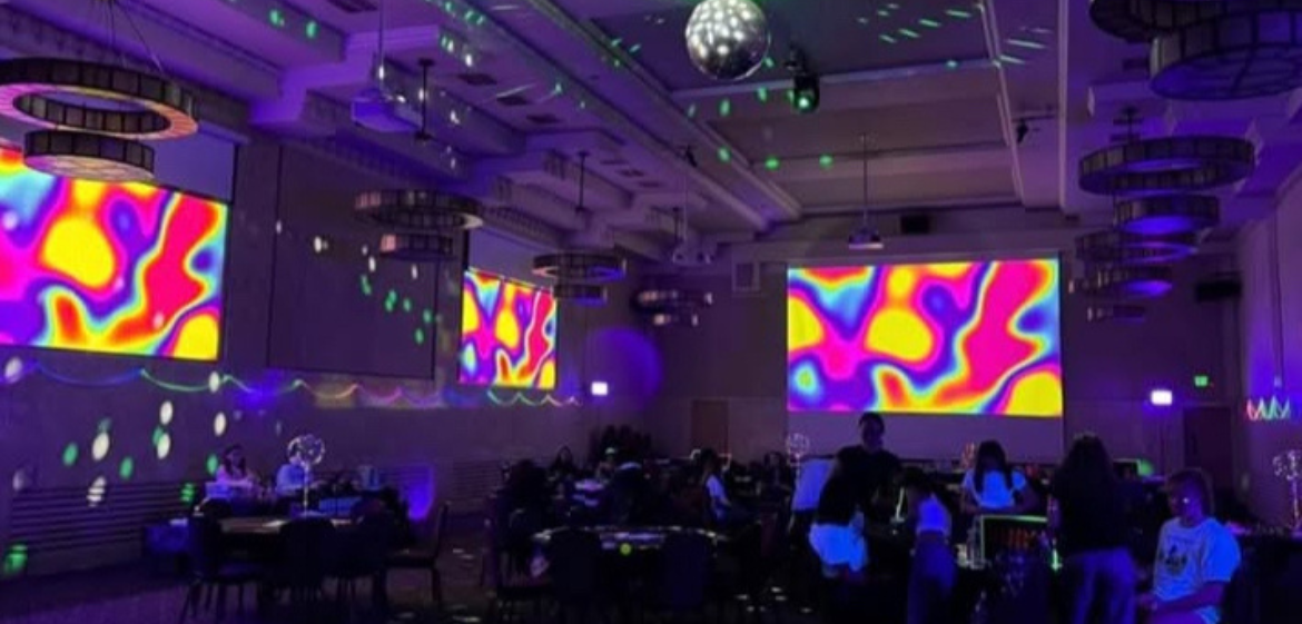 Dancing crowd in darkened room with projectors