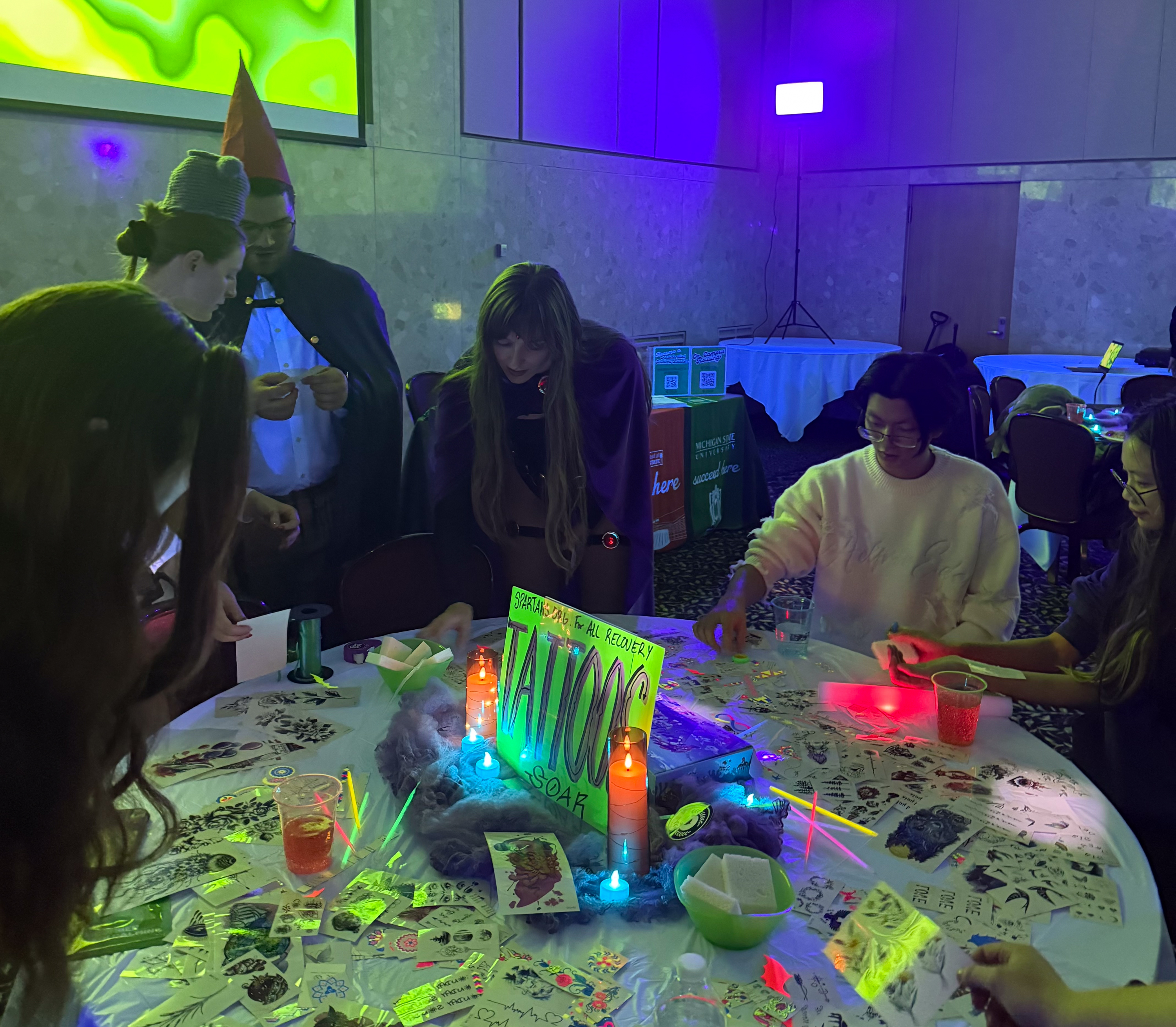 College students gather around a table of crafts and temporary tattoos.