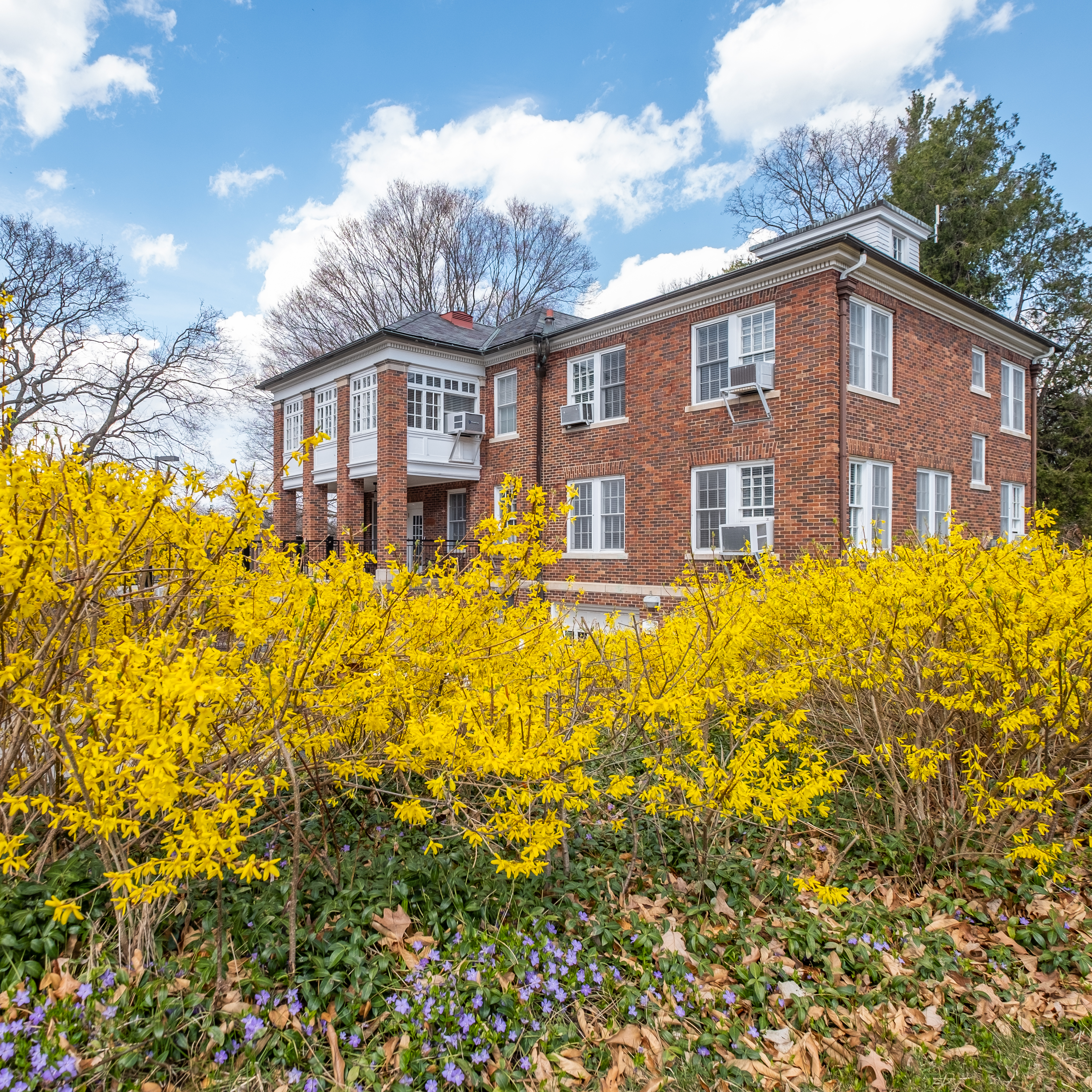 A two story brick building surrounded by yellow fall foliage