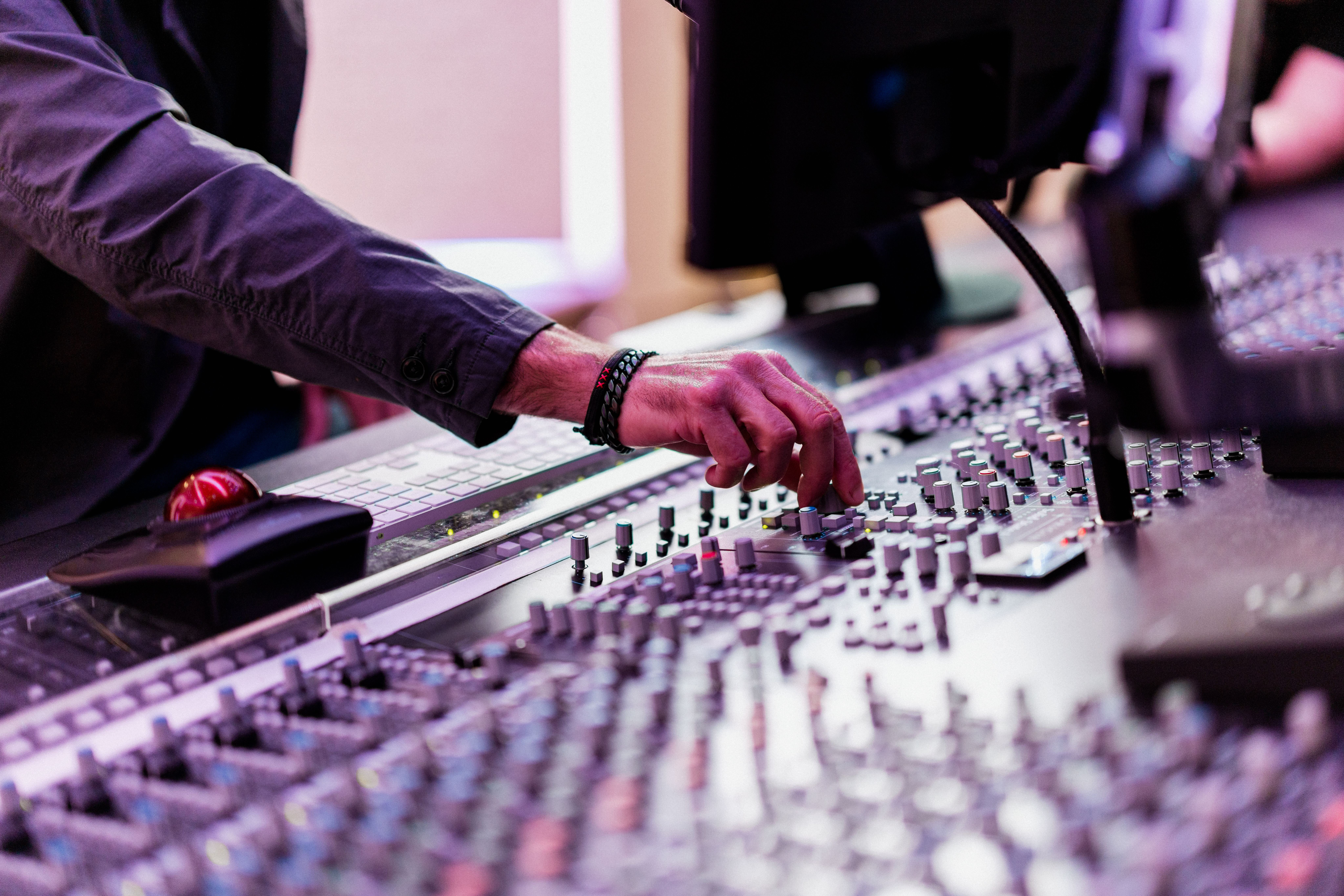 Paul Rosenberg adjusts audio levels on a professional sound mixing board, symbolizing his career in the music industry.