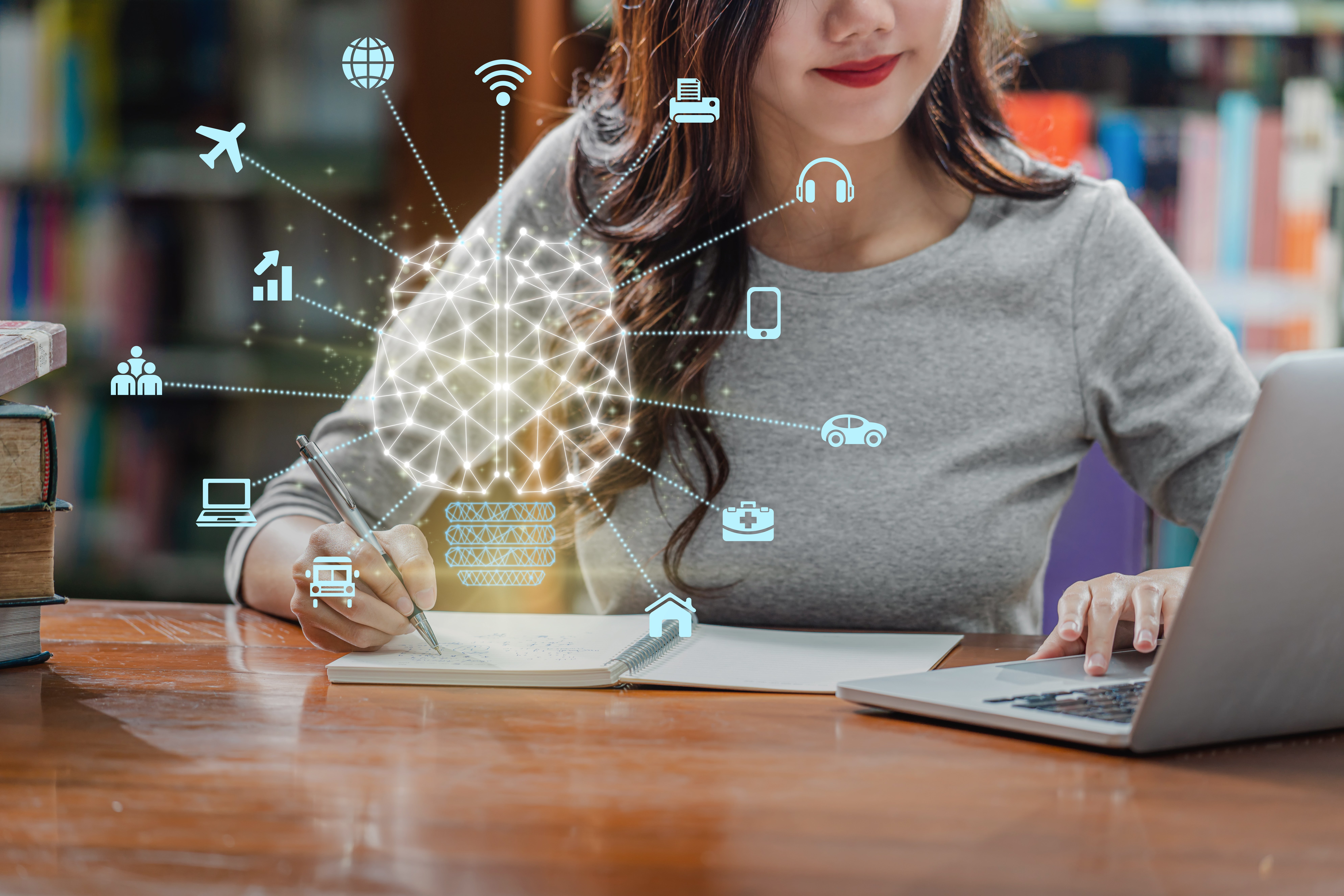 Woman sitting in front of a laptop with a holographic image of interconnected ideas displayed to the side. 