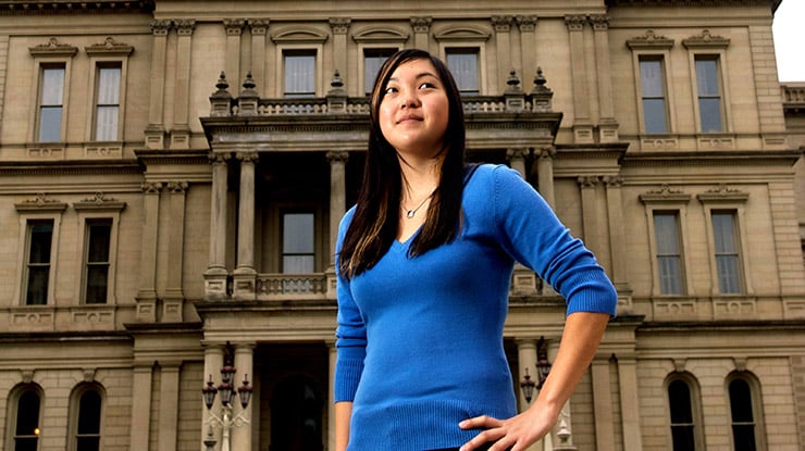 What is environmental economics? A student stands in a confident pose in front of a municipal building, ready to answer.